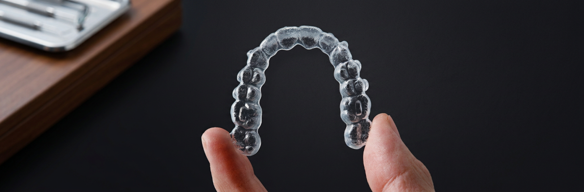 Invisalign Mississauga — patient holding a clear Invisalign aligner tray at North Star Dentistry, showcasing discreet orthodontic treatment planned with iTero 3D digital scanning by Dr. Mays Al-Saffar