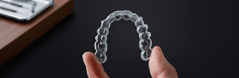 Invisalign Mississauga | Clear Aligner Treatment at North Star Dentistry with Dr. Mays Al-Saffar Invisalign Mississauga — patient holding a clear Invisalign aligner tray at North Star Dentistry, showcasing discreet orthodontic treatment planned with iTero 3D digital scanning by Dr. Mays Al-Saffar