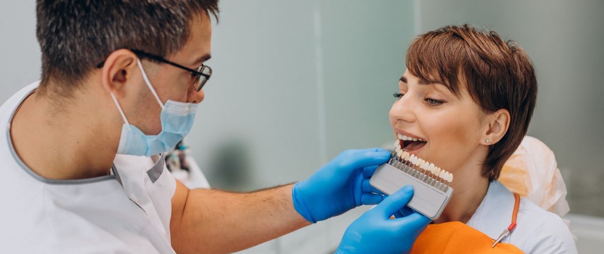 Dental veneers shade matching at North Star Dentistry Mississauga — a cosmetic dentist holds a porcelain veneer shade guide next to a smiling patient to select the perfect color match for composite, porcelain, E.max, or zirconia veneers